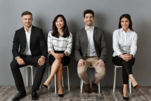 smiling interracial business people in formal wear looking at camera while waiting for job interview